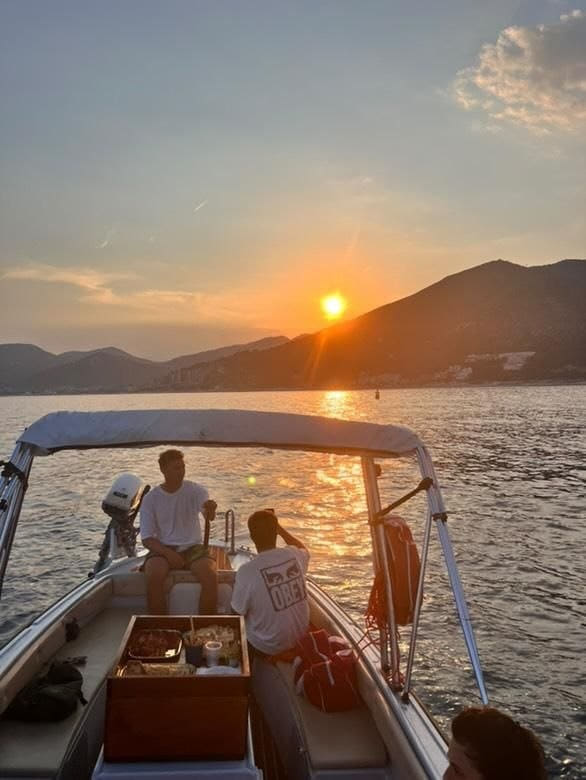 Luca e Andrea al timone del gozzo al tramonto, sulla rotta della Riviera di Ponente